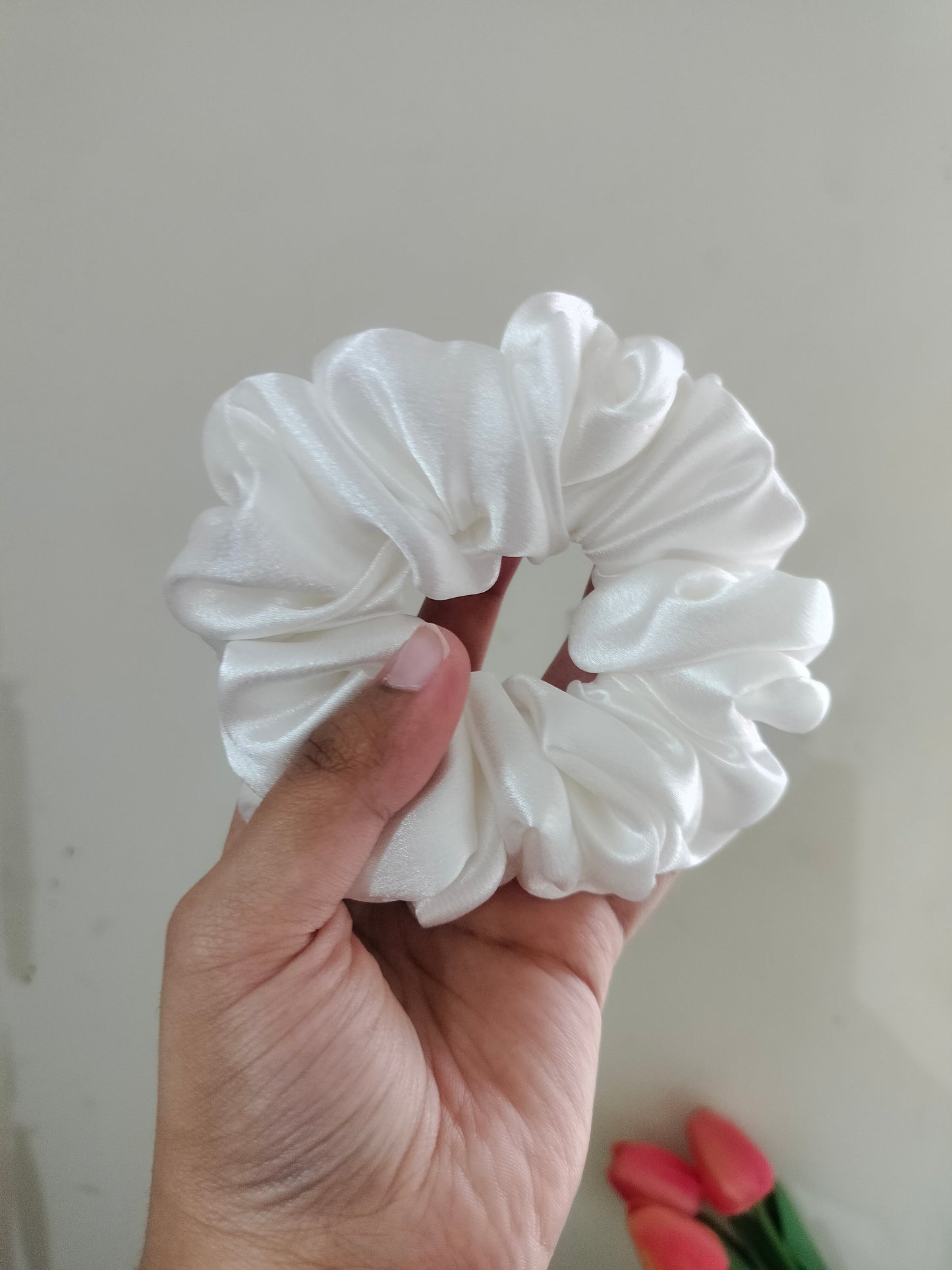 seller's hand holding a white hair scrunchie against a plain background