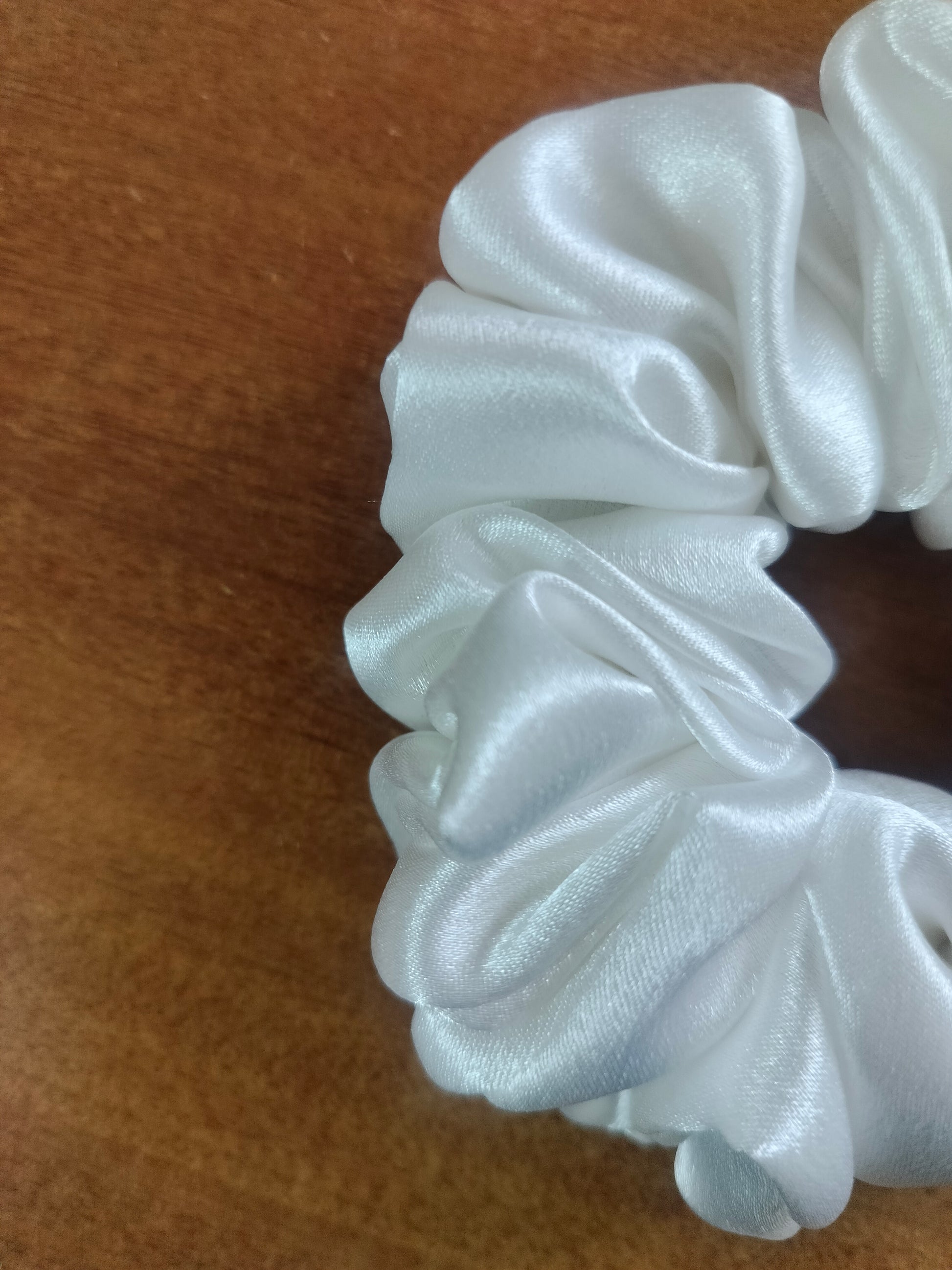 White silk scrunchie on a wooden surface